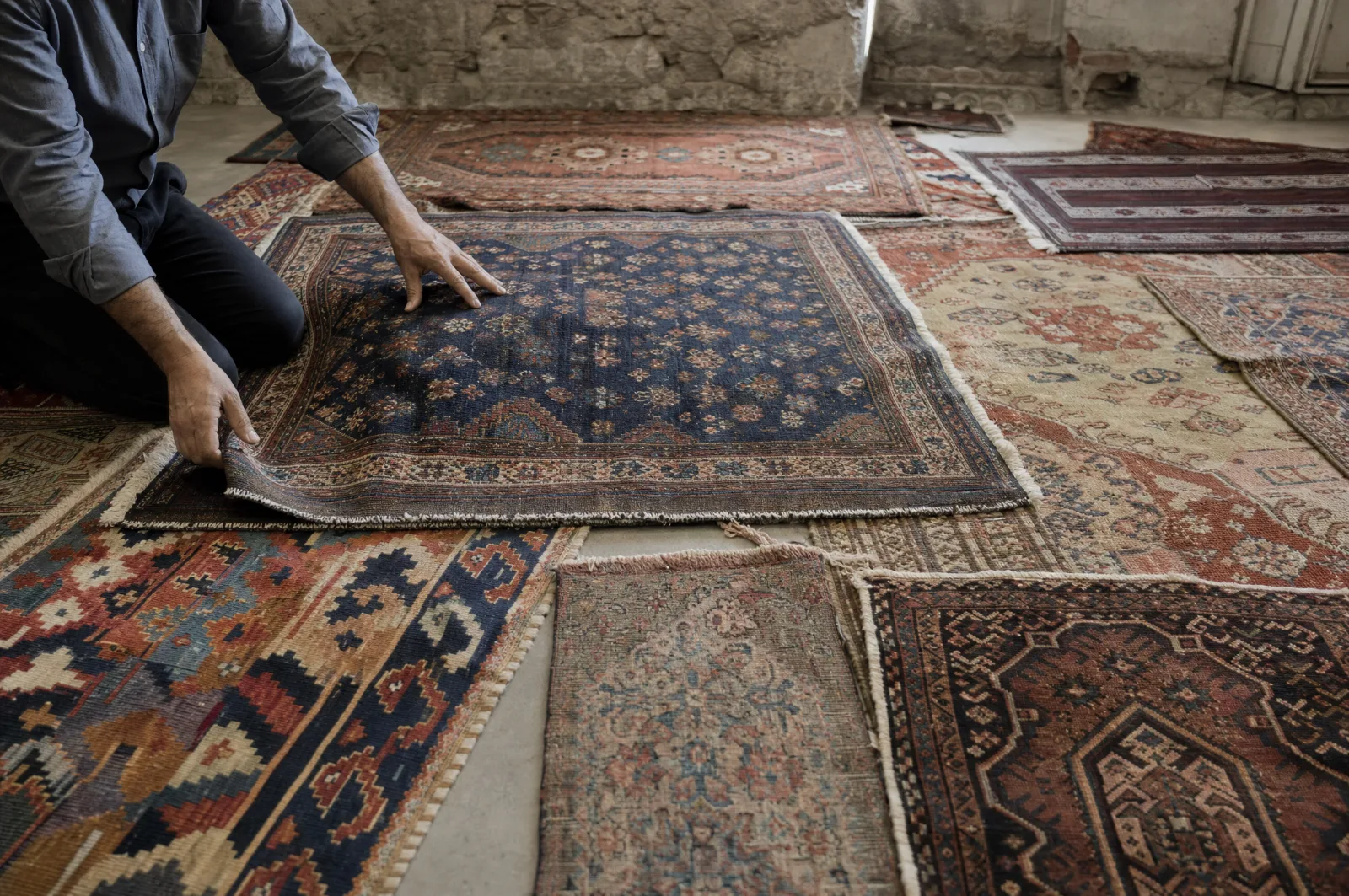 Plusieurs tapis anciens étalés dans un atelier de pierre pour estimation (illustration)