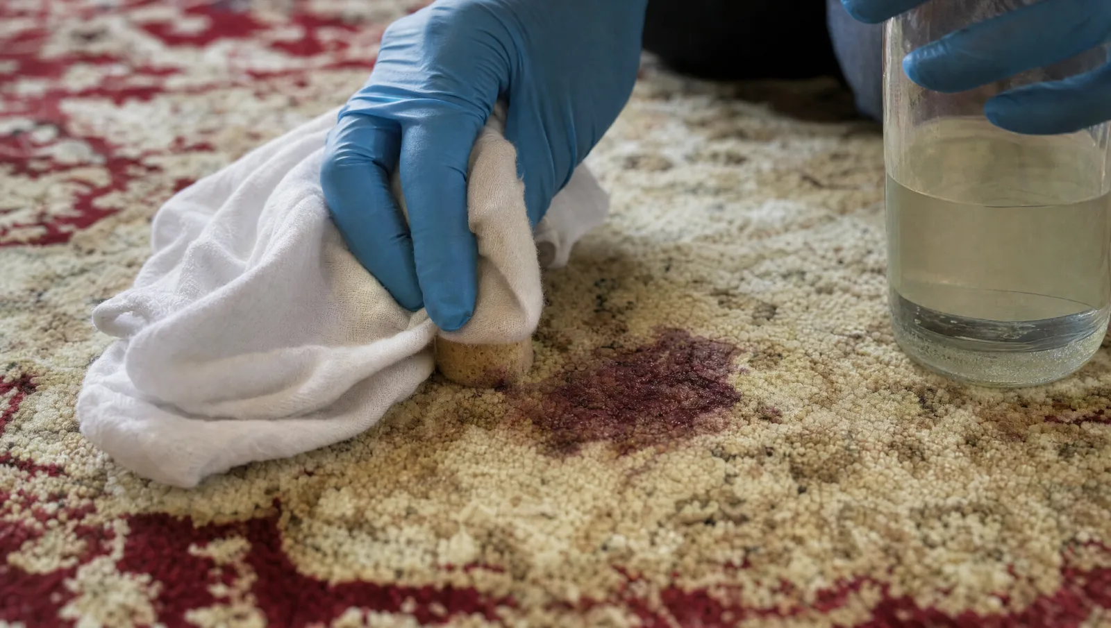 Détachage d'une tache de vin sur un tapis crème et bordeaux avec un linge blanc et une éponge (illustration)