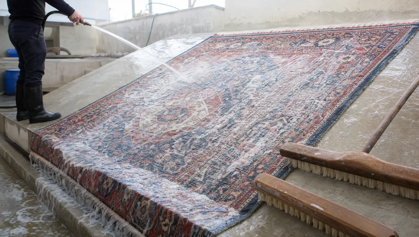 Lavage d'un grand tapis en laine sur une dalle inclinée, rinçage à l'eau claire dans un atelier lumineux (illustration)